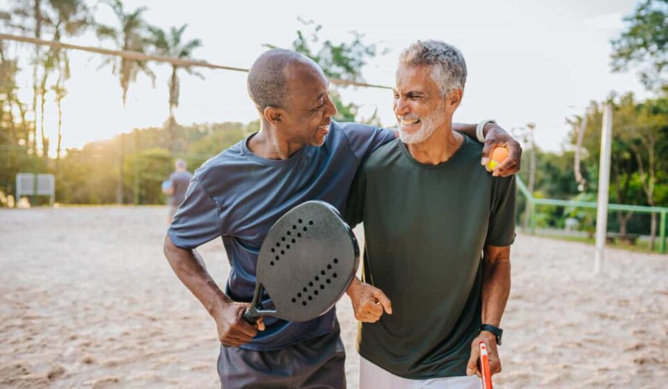 Two senior friends playing beat tennis on sand tennis court