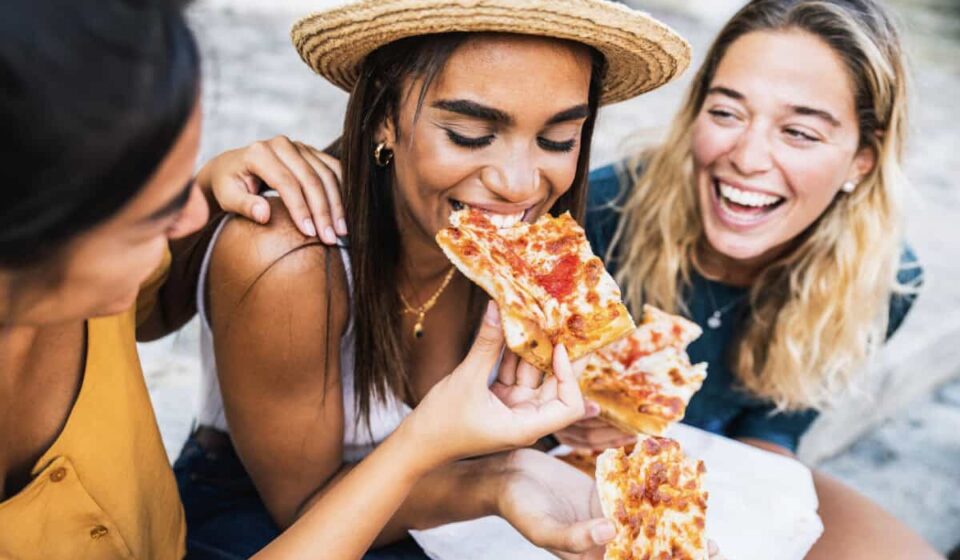 three friends eat pizza
