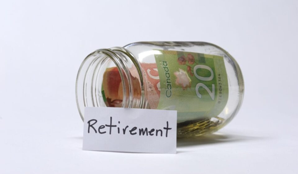 A glass jar resting on its side with Canadian banknotes and change inside.