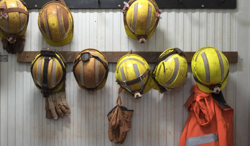 Safety helmets and gloves hang from a rack on a mining site.