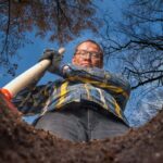 man with shovel stands by a hole