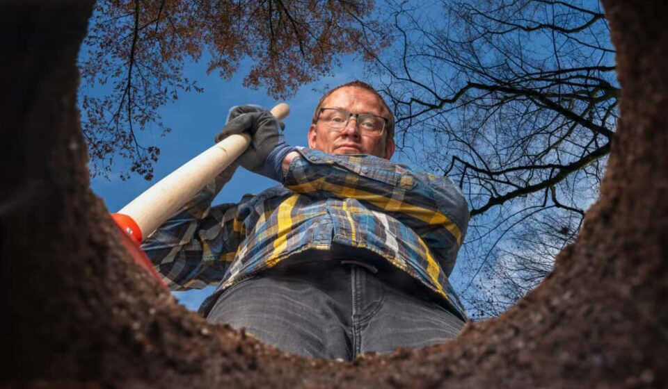 man with shovel stands by a hole