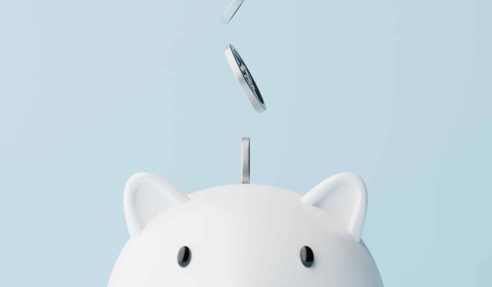Silver coins fall into a piggy bank.